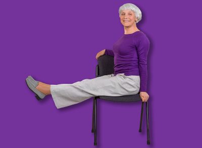 Happy charming beautiful elderly woman is doing exercise on a chair. Exercising gymnastics for health in the fitness room. Sports training.