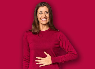 Elegant middle-aged Caucasian woman in studio setting touches tummy, smiles gently, eating and satisfaction concept.