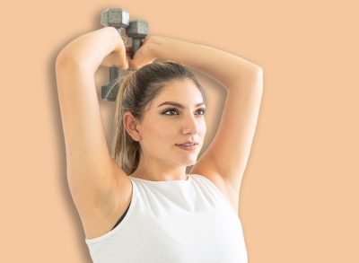 young girl exercising her forearms with dumbbells in a gym. Overhead Triceps Extensions