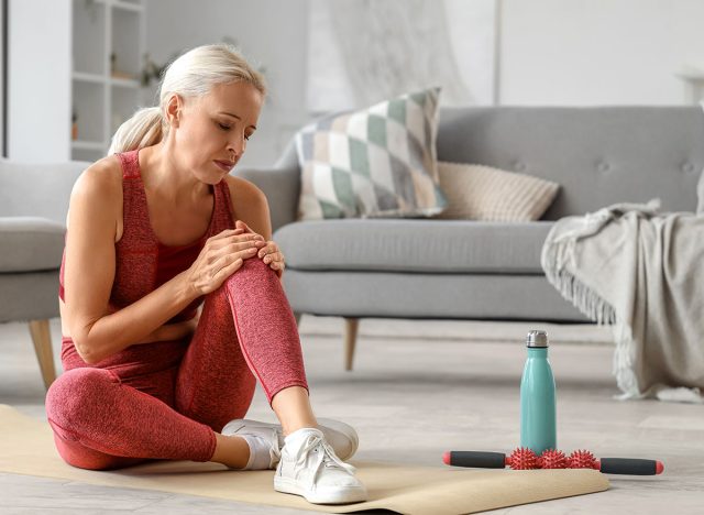 Sporty mature woman suffering from knee pain at home