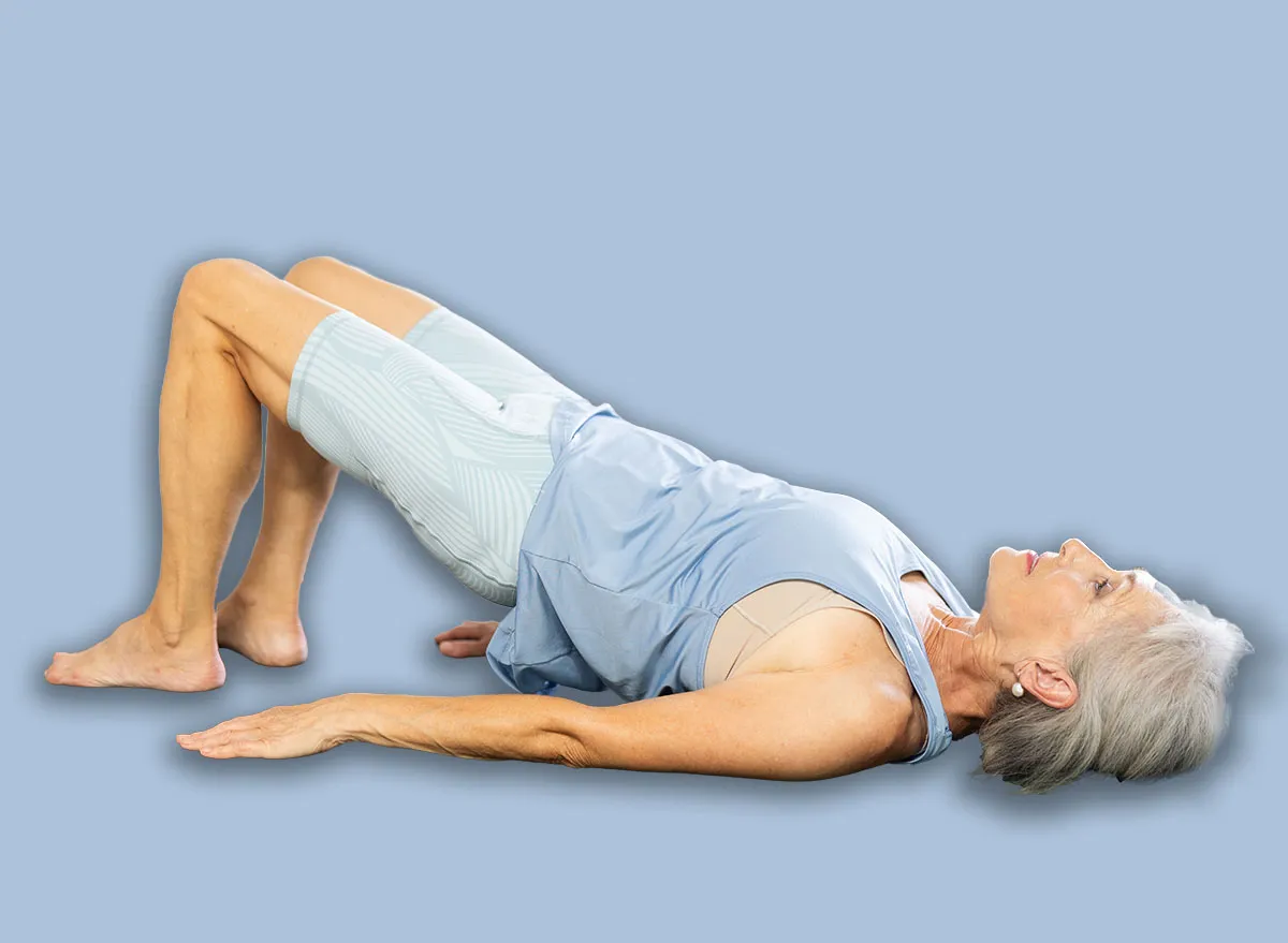 Three generations of women perform half bridge Setu Bandha Sarvangasana, glute bridge in gym. Multi generational family doing yoga together