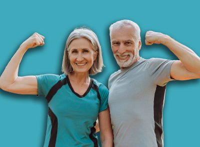 Smiling, attractive senior athletic couple flexing muscles in park, looking at camera outdoors, active lifestyle concept