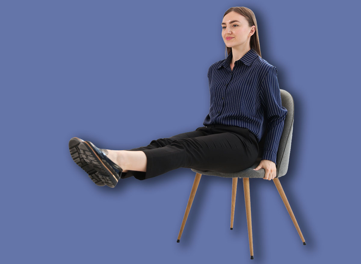 Beautiful woman exercising with chair in office