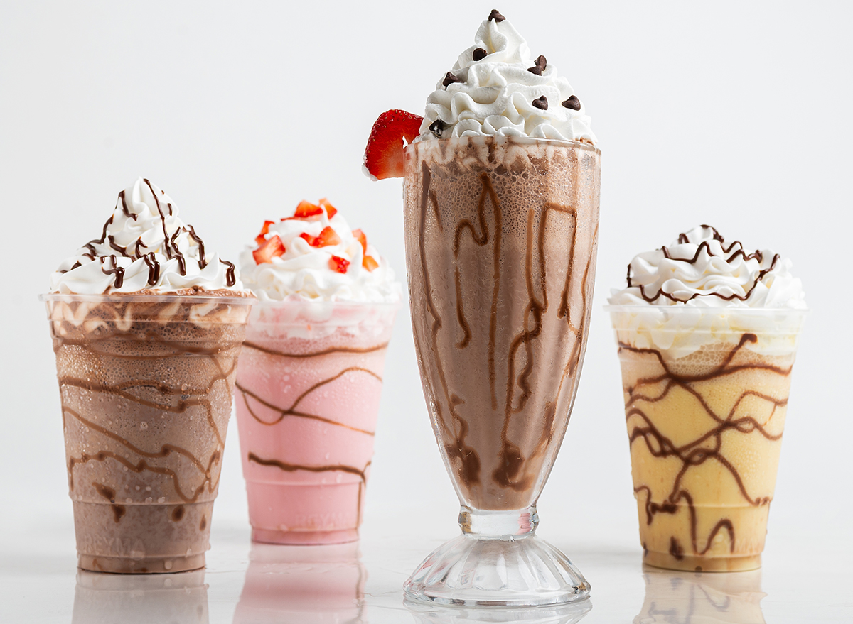 Four tempting milkshake variations: chocolate, strawberry, vanilla, and a mocha blend, each topped with whipped cream and chocolate drizzle