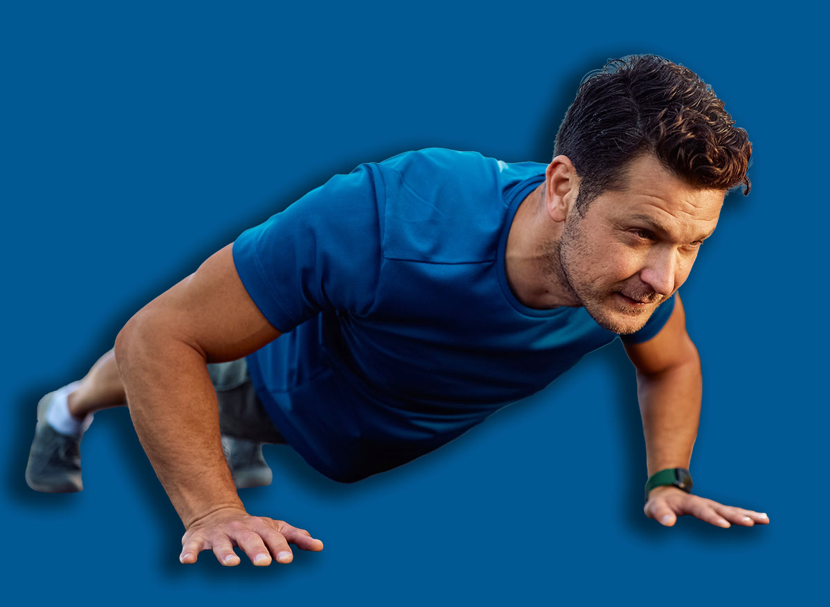 Male athlete exercising push-ups during strength training in outdoor gym. Copy space.