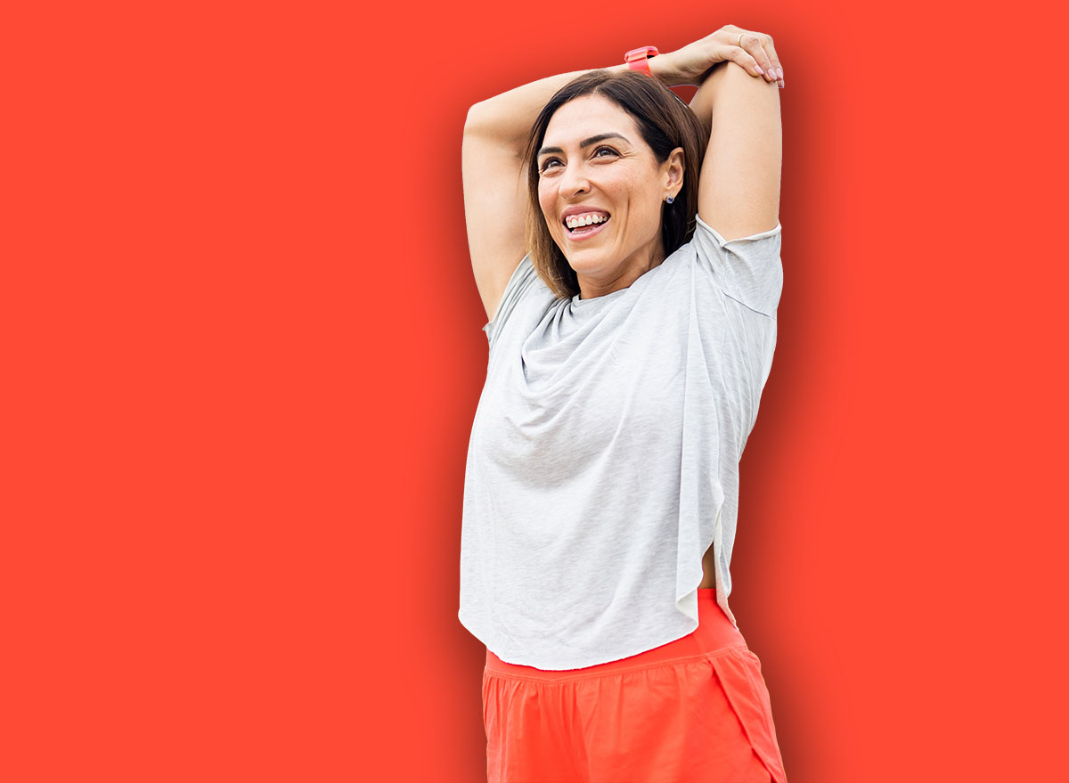 A woman between 40 and 50 years old is training outdoors in sportswear.The woman stretches her arms happily.Concept of middle-aged women doing sports.