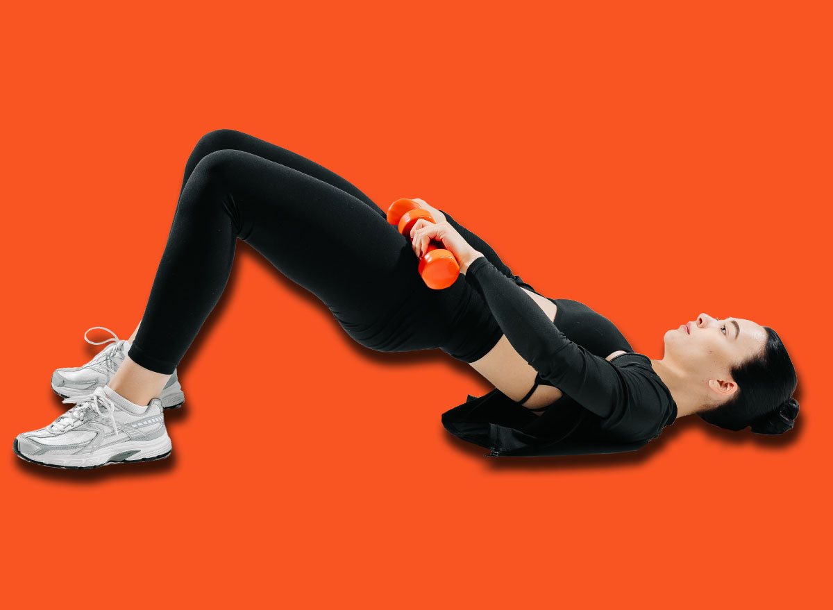 Sporty woman doing glute bridge exercise with orange dumbbells on white background. Concept of fitness, strength training, workout routine, and healthy lifestyle.
