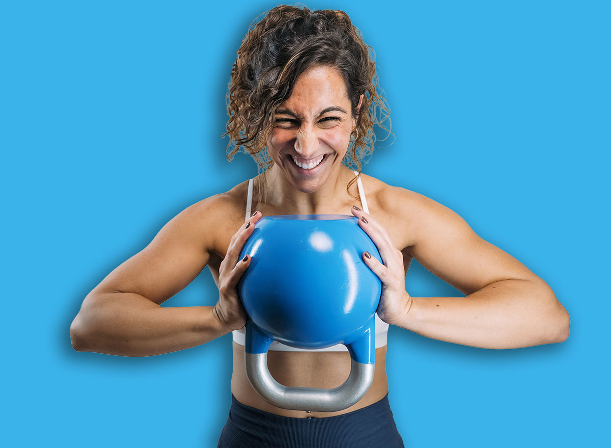 Woman powerfully holding kettlebell, showing strength during workout