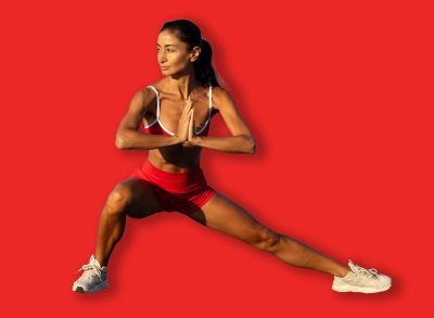 Fit woman stretching her legs in a wide lateral lunge on a sandy