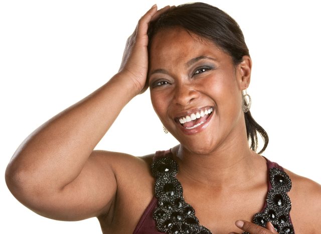Joyful lady with hand on forehead over white background