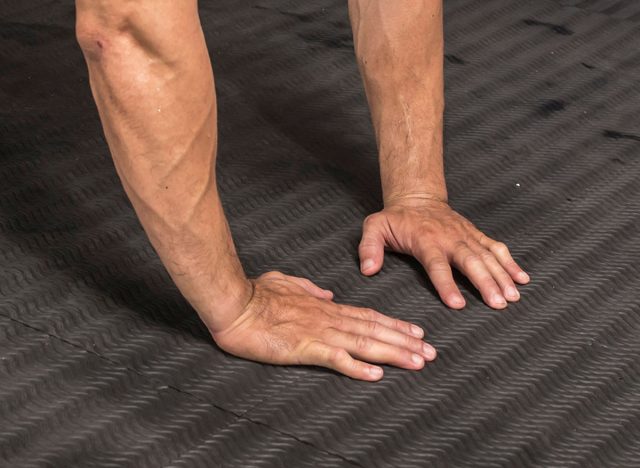 A fit asian man does close grip push ups at a MMA gym. Body weight calisthenics or HIIT workout. Training chest and triceps.