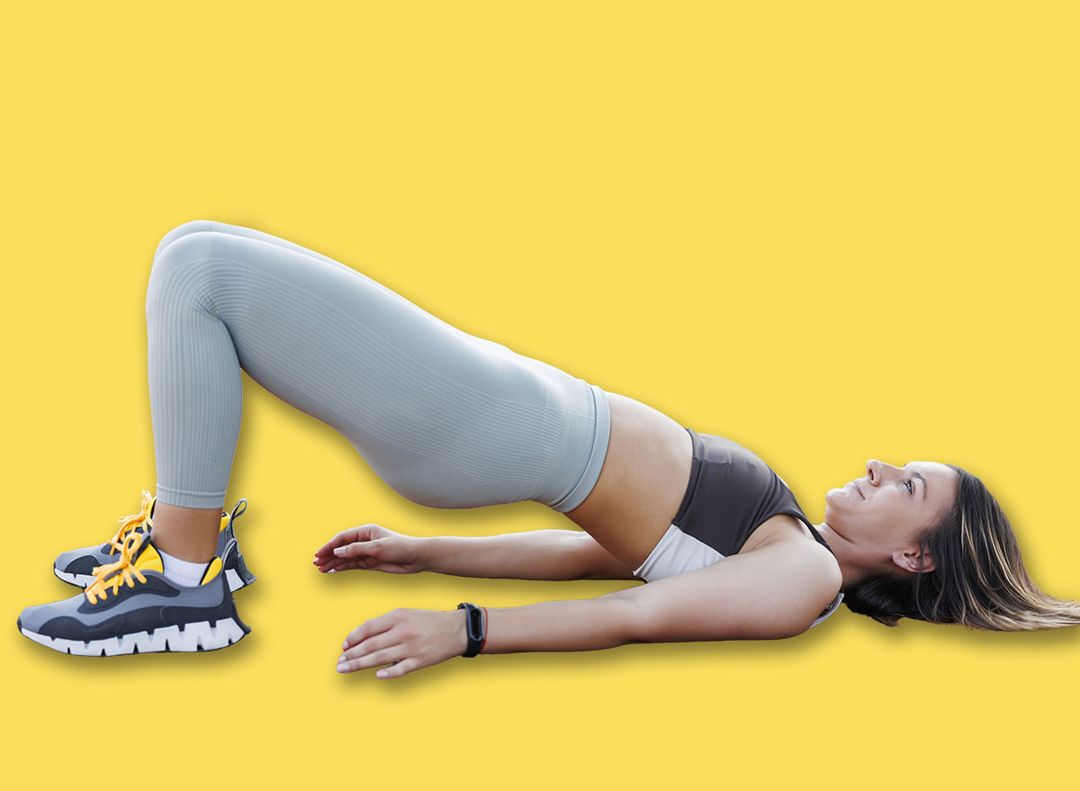 Active fit young woman in sports clothes doing an outdoor workout at basketball court, doing legs and glutes exercises using resistance band