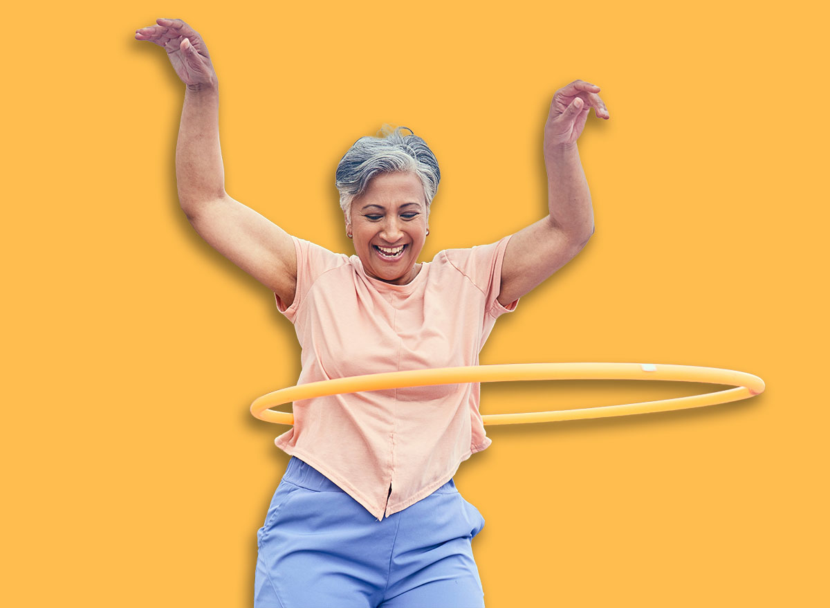 Senior woman, hoop and fitness outdoor with smile, training and playful on balcony, mountains and healthy. Mature lady, exercise and happy for wellness, stomach workout and toys on rooftop in Hawaii