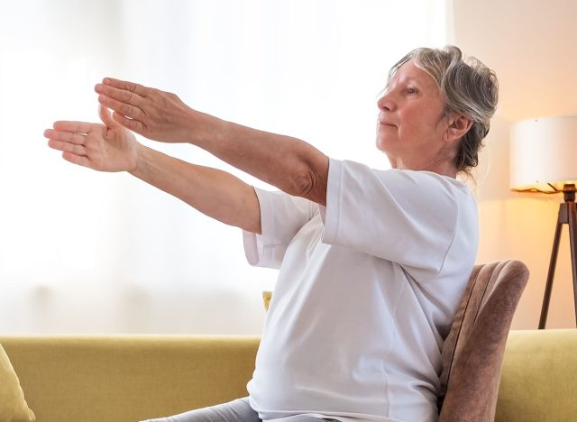 Senior caucasian woman doing yoga at home on chair