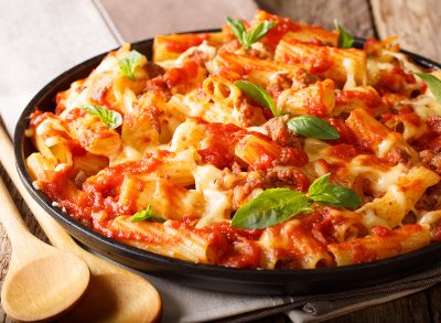 Spicy pasta ziti with minced meat, tomatoes, herbs and cheese close-up on a plate. horizontal