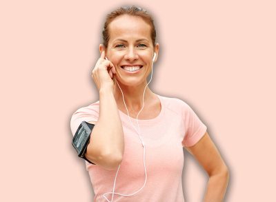 fitness, sport and healthy lifestyle concept - smiling woman with earphones wearing armband for smartphone and listening to music at summer park