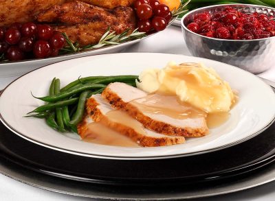 Sliced turkey with mashed potatoes and gravy and green beans.