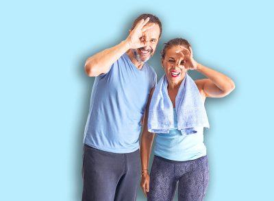 Middle age sporty couple standing before do exercise at gym doing ok gesture with hand smiling, eye looking through fingers with happy face.