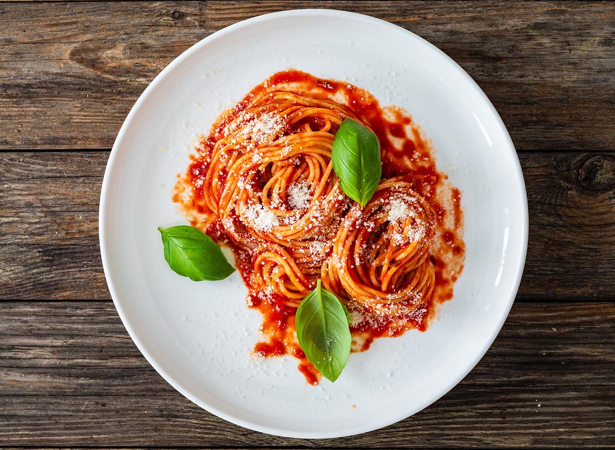 Spaghetti marinara - noodles with tomato sauce, parmesan cheese and basil leaves served on wooden table