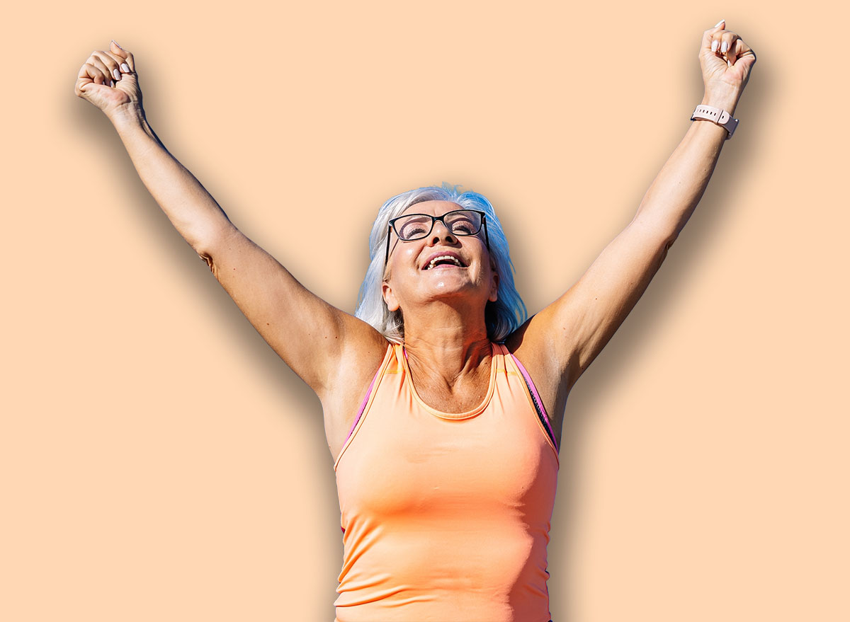 Sportive elder woman feeling free raising arms and fists