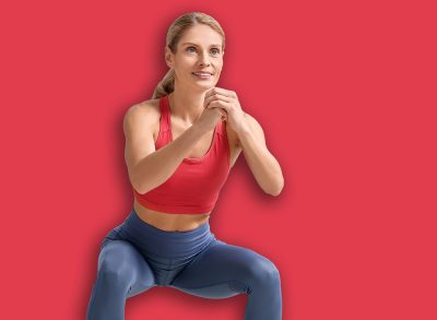 Fit woman doing squats with fitness elastic band at home