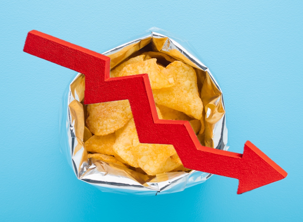 Opened,Foil,Bag,With,Yellow,Potato,Chips,On,Light,Blue