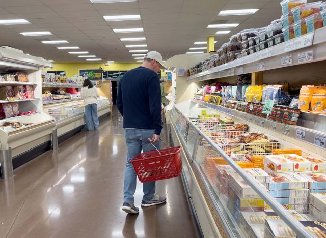 customer inside Trader Joe's Grocery store shopping for frozen meals in freezer aisle, packaged ready-made dinners or organic microwave meals