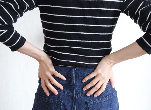 Woman holding her waist, image of lower back pain