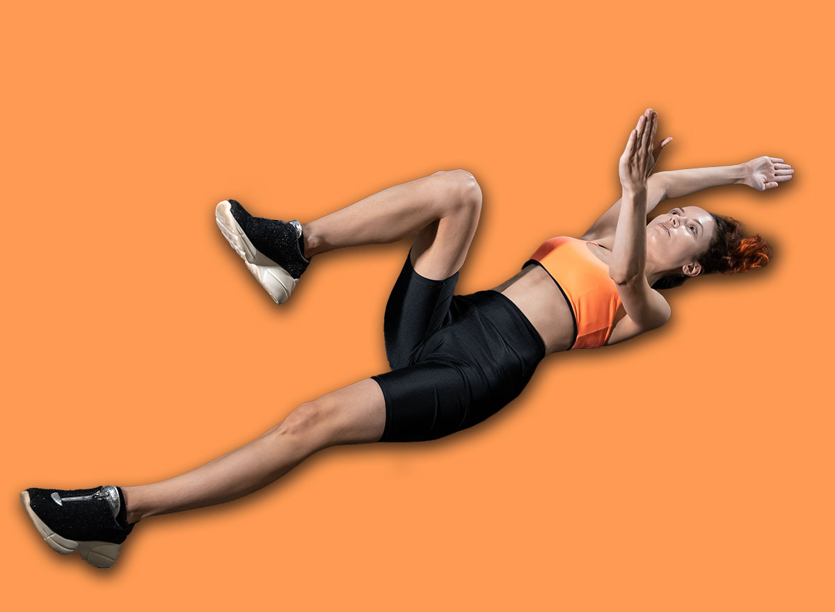 young woman exercising dead bug with personal trainer in gym