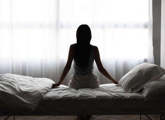 Silhouette of a Woman Sitting on Bed in Morning Light