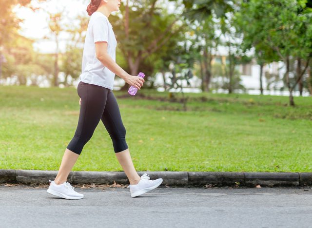 Woman walking in the park with bottle water in summer health care concept.