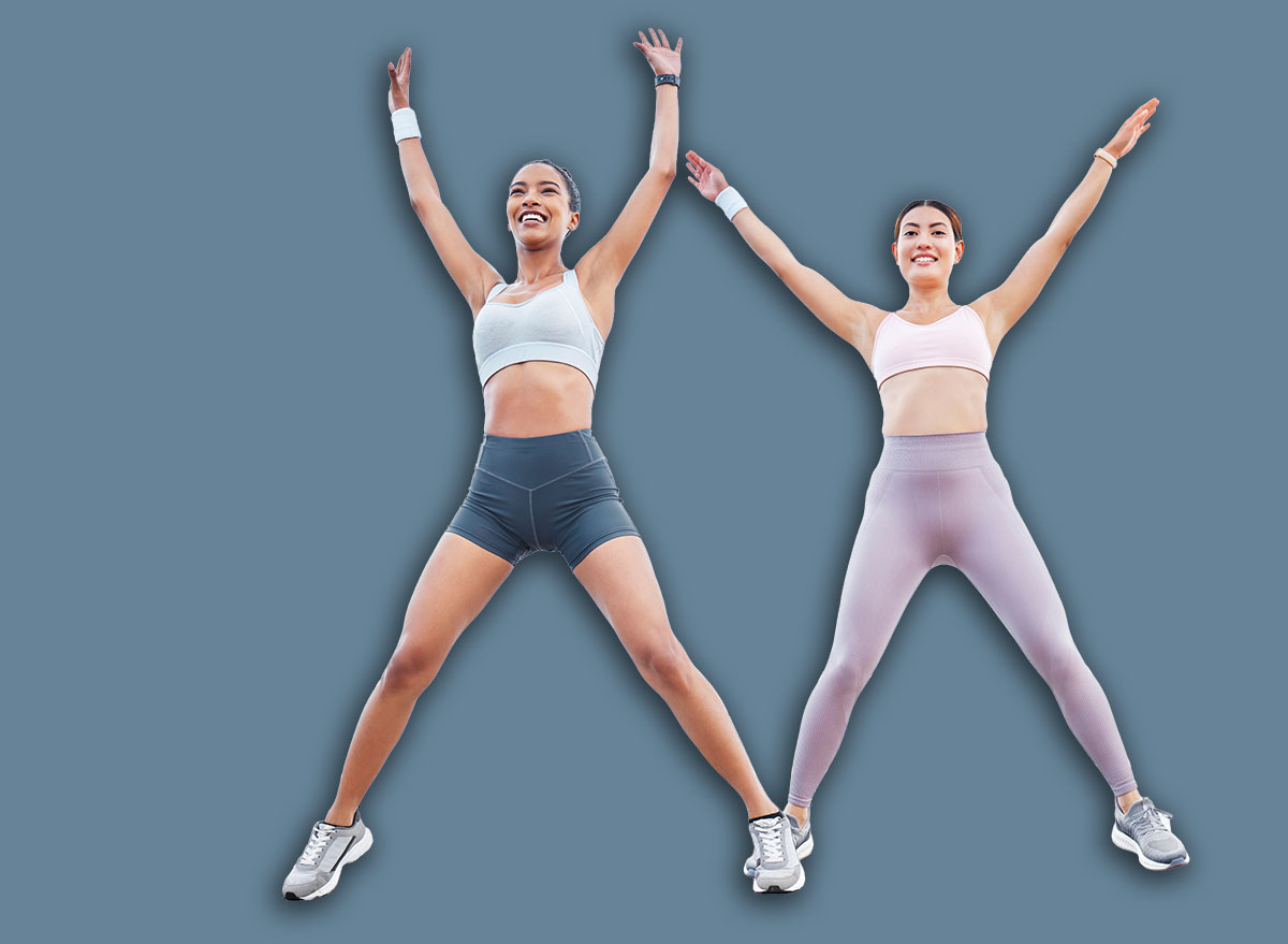 Jumping jack, fitness and women training cardio, happy with workout and smile during exercise in the city by the ocean. Young friends with energy for sports collaboration and stretching in the street