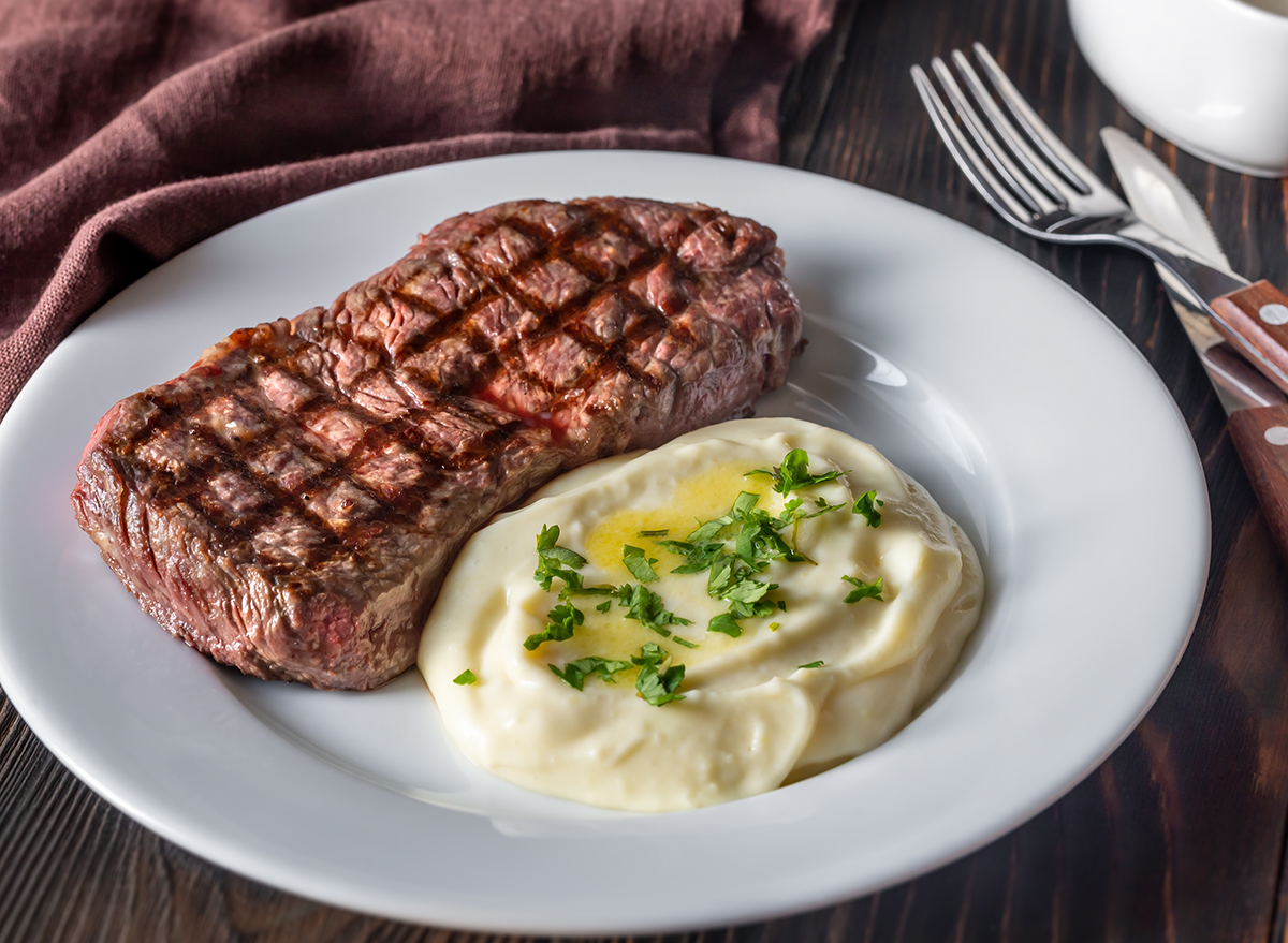 Strip steak with celery puree on white plate