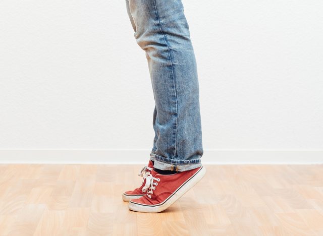 Man on tip toes, anonymous bottom half crop, indoors studio people shot.