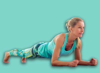 Full length shot of attractive middle aged woman doing plank exercises on yoga mat in the fitness studio.
