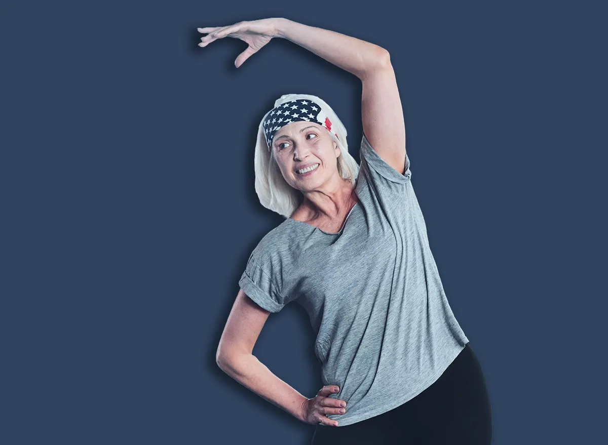 Sport is life. Positive minded woman grinning broadly and looking somewhere while doing side bend exercises in a gym.