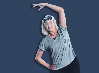 Sport is life. Positive minded woman grinning broadly and looking somewhere while doing side bend exercises in a gym.