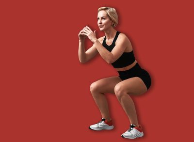 Smiling woman doing squats during workout. Fitness workout. Sport woman doing squat leg exercise at gym.