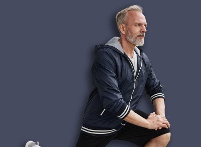 Fit senior man holding static lunge position strengthening leg muscles while working out together with female partner at city park