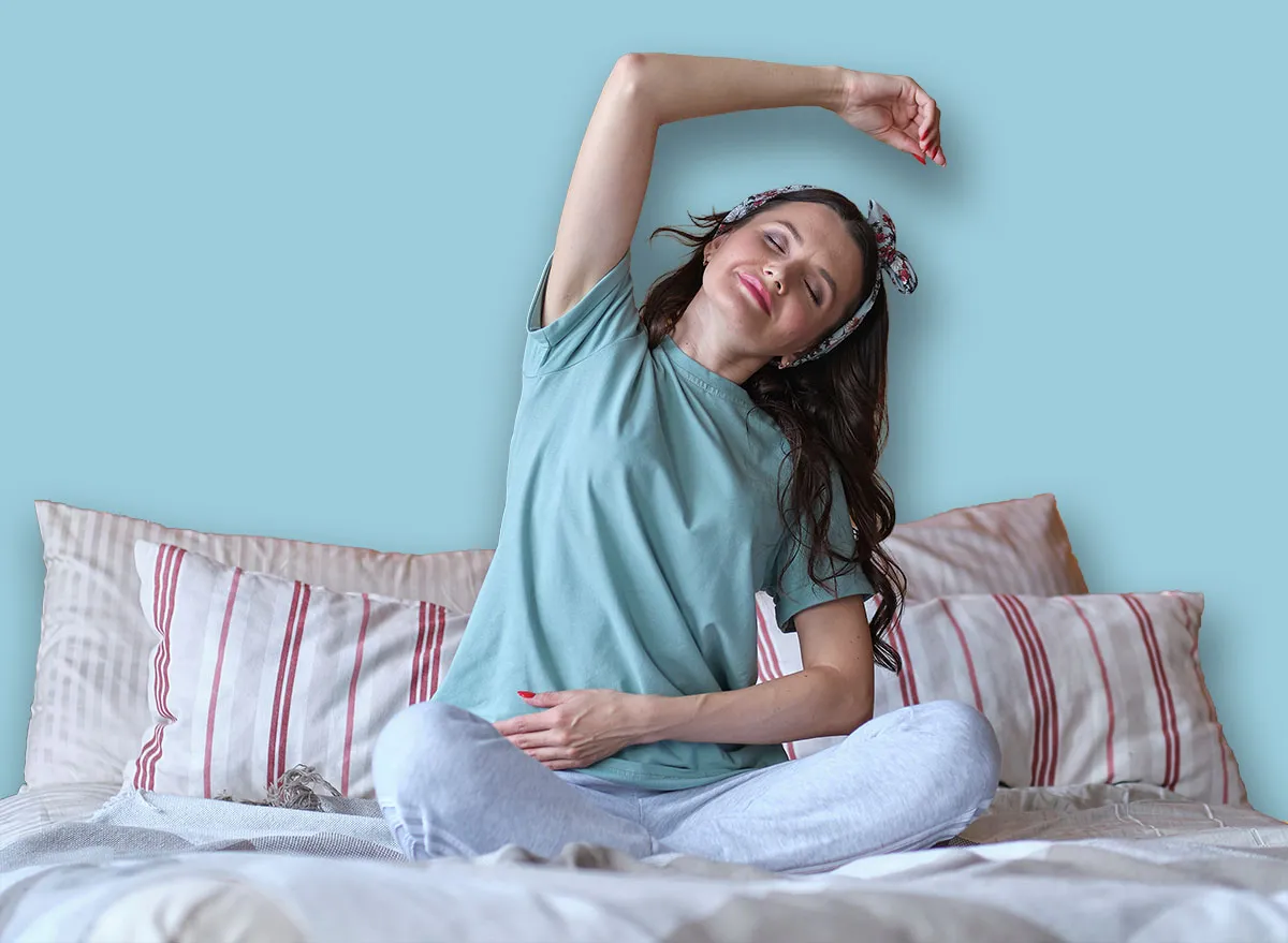 middle aged Woman doing yoga exercise on bed at home. Morning workout in bedroom. Healthy and sport lifestyle.