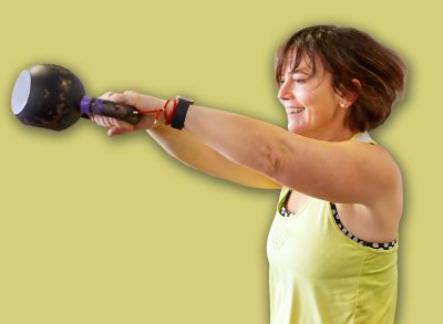 Mature woman performing a kettlebell swing exercise, focusing on fitness and strength training