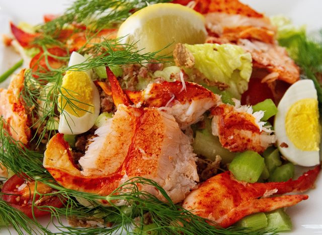 Lobster salad. Claw meat. Romaine lettuce, boiled egg, tomatoes, celery, bacon, lemon and dill. Healthy lunch or dinner. Nutritious eating. Luxury meal. Close up. Delicious. Macro.