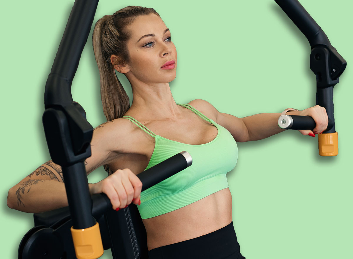 Sporty woman exercising chest press machine in modern gym.