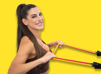 Smiling woman performing resistance band rows during fitness session, showcasing toned arms and posture
