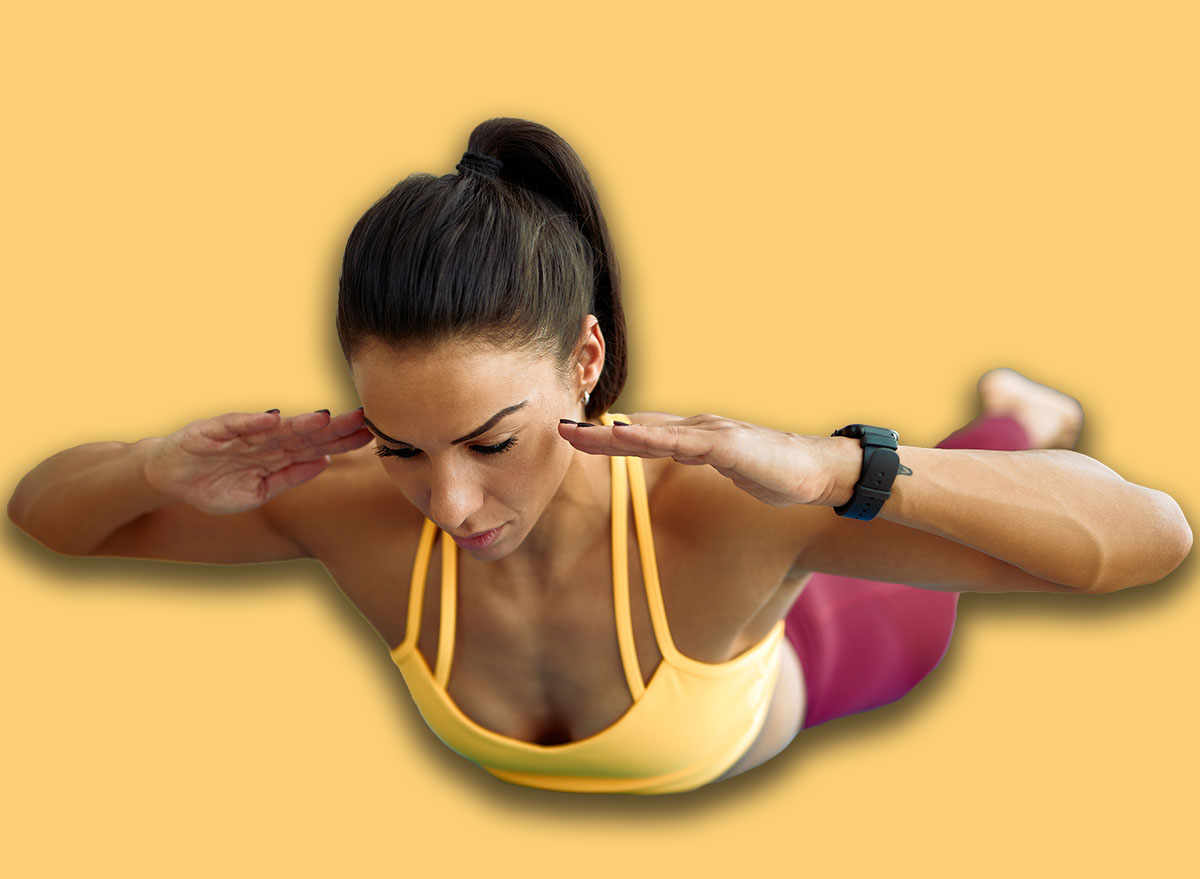 Young athletic woman doing back-extensions while working out in the living room.