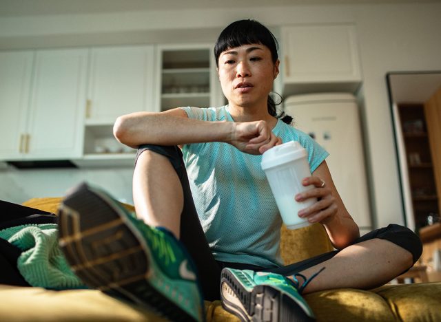 Adult woman resting after workout on couch at home, focused