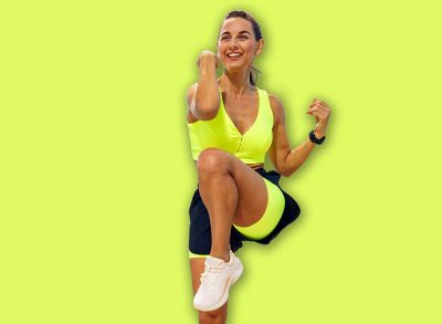 Fit woman exercises by the seaside on a sunny day with bright attire while enjoying outdoor fitness