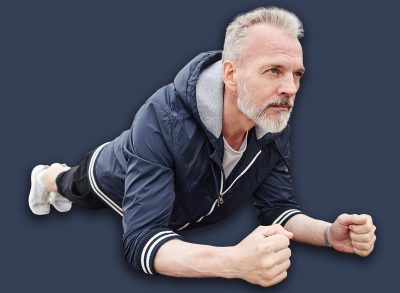 Sporty determined elderly man holding plank position on yoga mat strengthening core muscles during everyday workout at city park