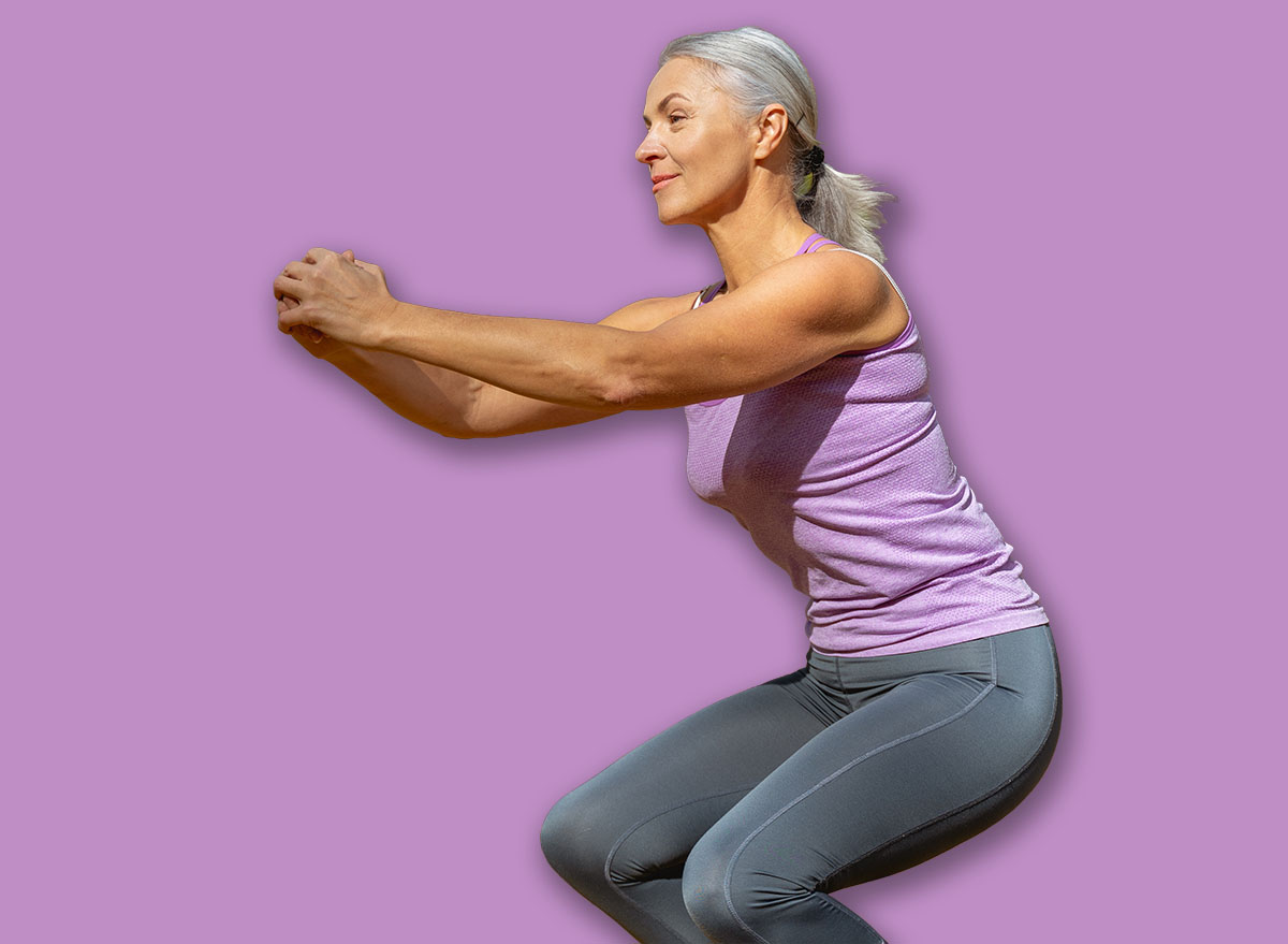 Pretty athletic Caucasian woman with clasped hands squatting