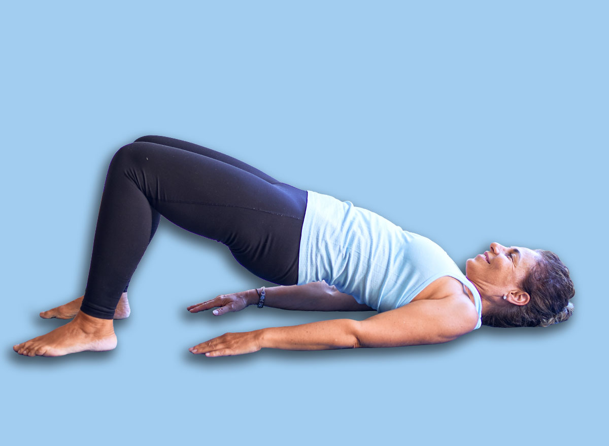 Middle age beautiful sportwoman smiling happy. Lying down on mat practicing yoga doing bridge pose at gym